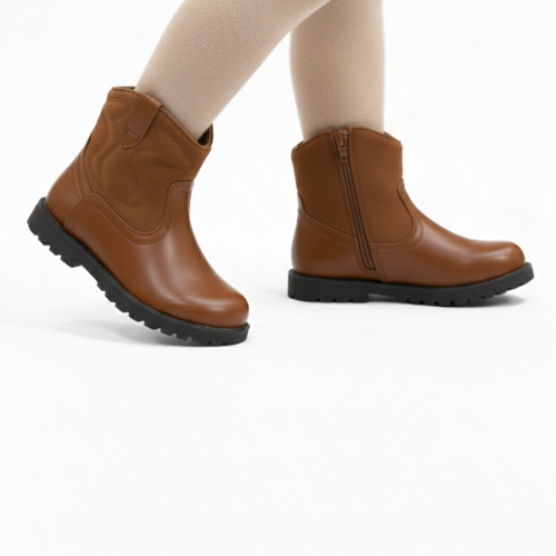 Gros plan sur bottine enfant marron posée sur fond bois, montrant la texture suédine et la finition cuir.